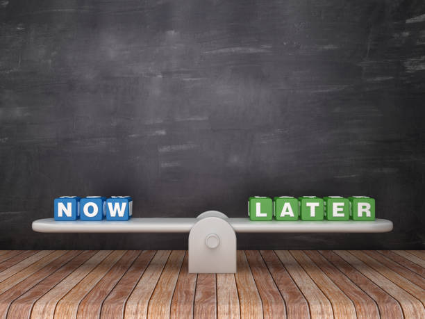 istock Seesaw Scale with NOW LATER Cubes on Chalkboard Background - 3D Rendering 1140443857