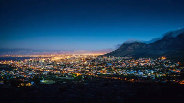 Beautiful illuminated Cape Town Cityscape Panorama at Twilight. Glowing City Lights of the ‚Mother City’ under the Table Mountain. Cape Town, Western Cape, South Africa, Africa.