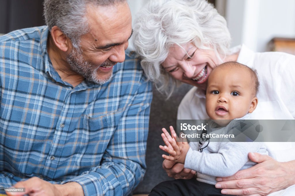 Grandma and Grandpa will always love you A retired senior couple is babysitting their grandchild. The couple is laughing and holding the baby while sitting on the couch. The playful child is clapping. Will - Legal Document Stock Photo