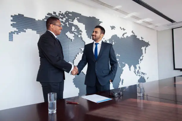 Photo of Businessmen shaking hands at conference table