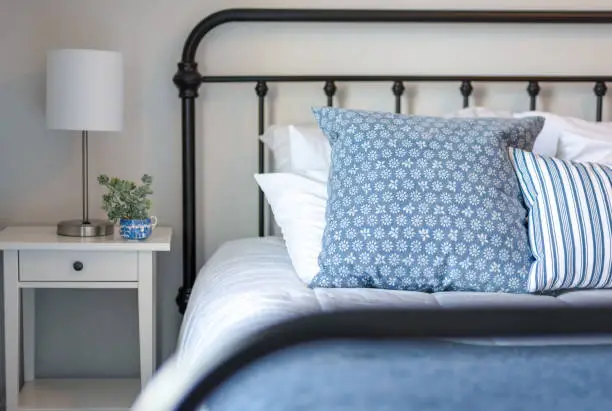 Iron bed with blue and white bedding and simple white nightstand - bedroom design