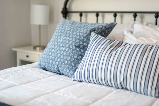istock Closeup of comfortable bed with blue and white pillows 1140460233