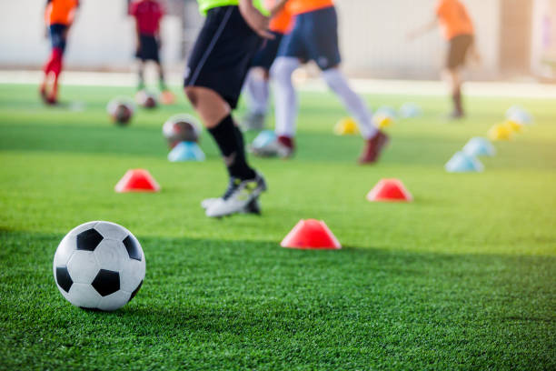istock Soccer ball on green artificial turf with blurry of maker cones and player training 1140460276