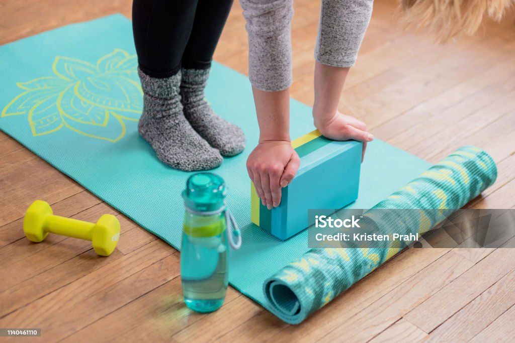 Girl with hands on yoga block stretching Young woman on exercise mat, hands on yoga block stretching - fitness healthy lifestyle concept Yoga Block Stock Photo