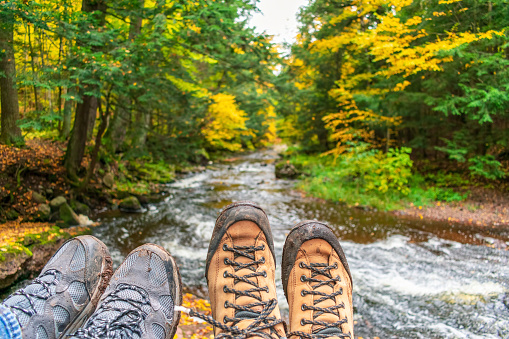 Muddy hiking boots over forest stream in fall - outdoor adventure and recreation