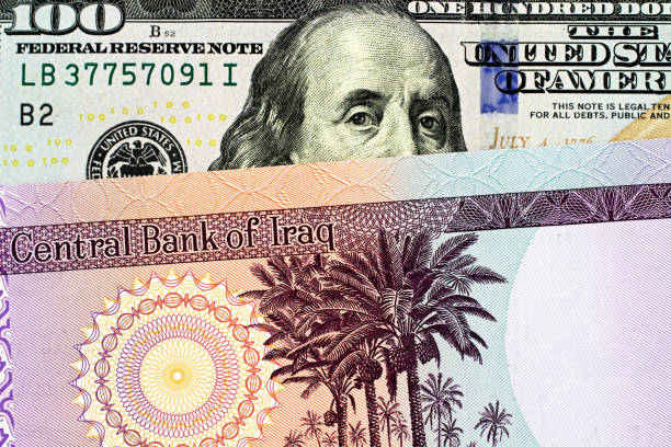 An Iraqi fifty dinar bank note with an American one hundred dollar bill A blue American one hundred dollar bill with an Iraqi fifty dinar bank note close up in macro dinar stock pictures, royalty-free photos & images