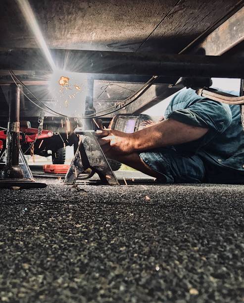 Man welding his trailer frame. Man welding his trailer frame after his trailer broke while driving welding helmet stock pictures, royalty-free photos & images