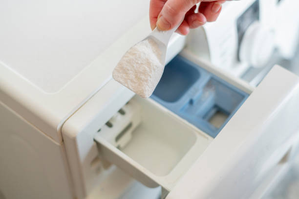 versez la poudre de lavage à la main dans la machine dans la lessive - laundry detergent cleaning product concepts measuring cup photos et images de collection