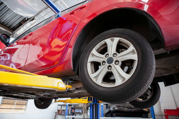 istock Red car lifted on hydraulic car lift in a workshop during routine service 1140465232