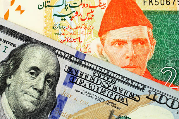 A close up image of a Pakistani rupee bank note with an American one hundred dollar bill stock photo