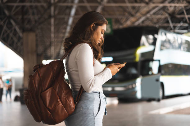 mujer esperando el autobús en la estación de autobuses - estación de autobús fotografías e imágenes de stock