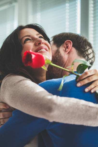 istock Woman hugging man, holding red rose 1140471709