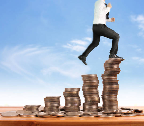 istock Businessman walk on stack of coins which grows success 1140480376