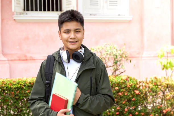 istock Handsome young asian schoolboy with book and backpack smiling 1140485152