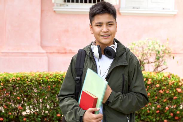 istock Handsome young asian schoolboy with book and backpack smiling 1140487626