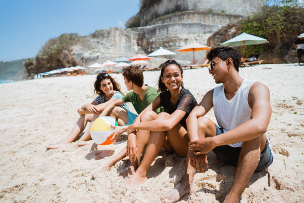 enjoy the beach with friends sitting on sand  and look to see a cross the sea