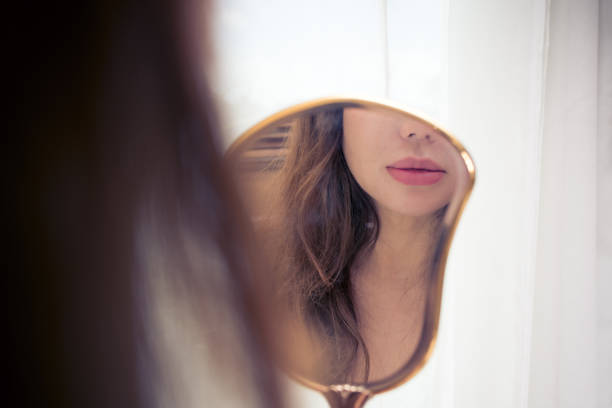 istock Woman looking at her reflection in an antique hand mirror 1140489308