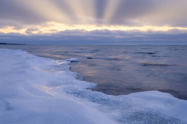 istock ice and snow on a beach in the foreground, sun rays shining through the clouds in the background 1140508906