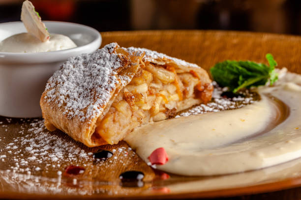 Photo of Concept of Austrian cuisine. Apple pie puff pastry. Strudel with apples and cinnamon. Serving dishes in a restaurant with a scoop of ice cream and sugar powder. copy space