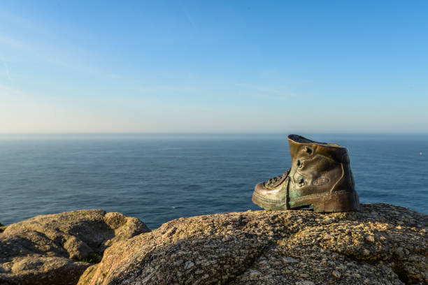 A cast bronze boot on the rocks at the end of camino de santiago - Finisterre