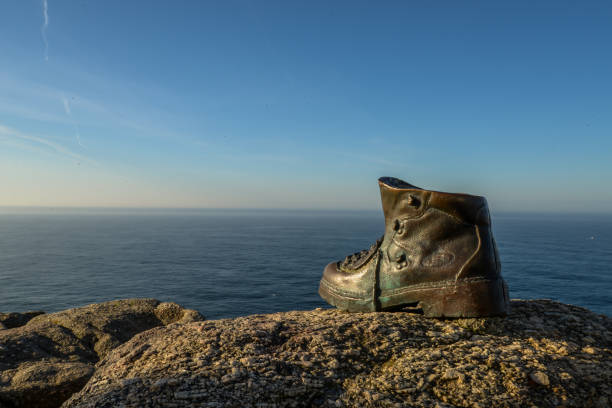 A cast bronze boot on the rocks at the end of camino de santiago - Finisterre
