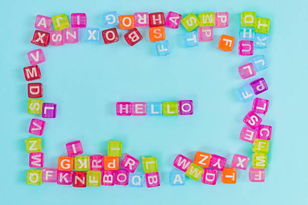 istock Multicolored plastic cube beads with letters scattered on blue background and words hello. English Alphabet background texture 1140515019