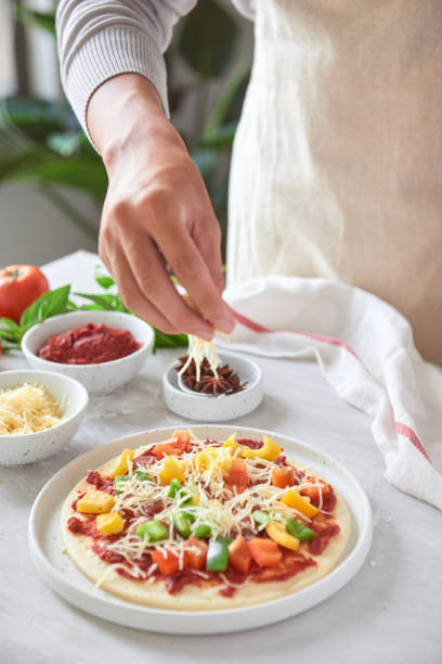 baker's hand placing ingredients on pizza - pizza sauces chef making imagens e fotografias de stock