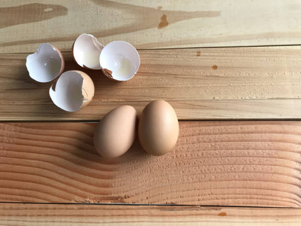 istock two fresh chicken eggs with four pieces of eggshells on natural wooden table 1140518464