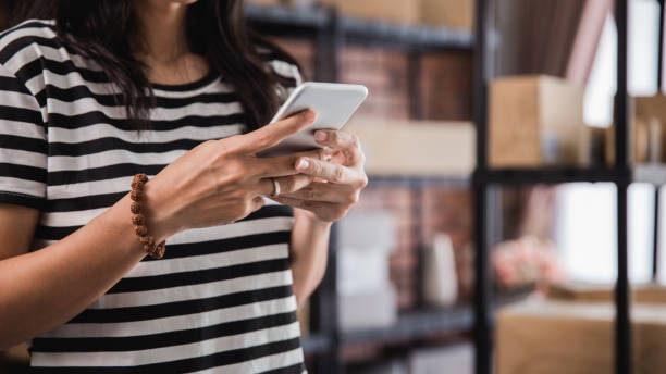 istock hand using smart phone and packages shelf in background 1140519820