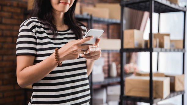 istock hand using smart phone and packages shelf in background 1140519881