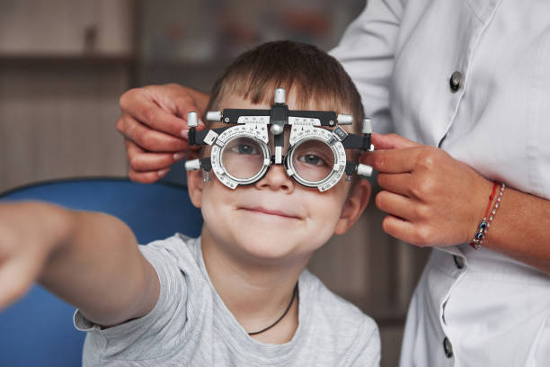 istock Kid smiling and raising hand while undergoing eye test with phoropter 1140521688