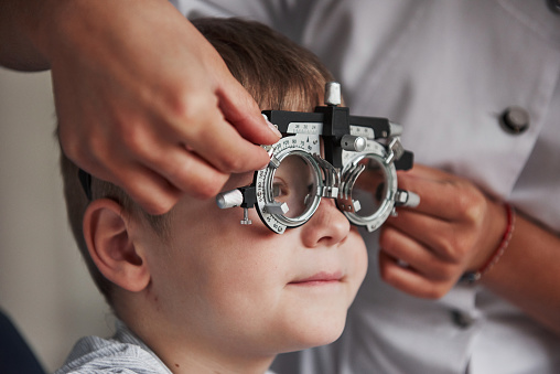 Close up portrait of child in special glasses in ophthalmologist cabinet.