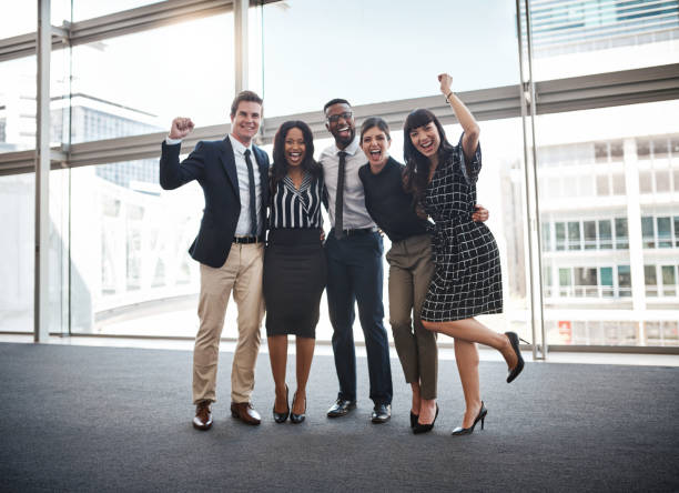 Success happens when great people come together Shot of a group of well-dressed businesspeople standing together cheering group of people success looking at camera stock pictures, royalty-free photos & images