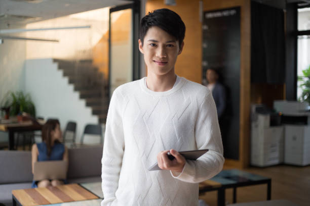 istock Young Asian Male Looking at Camera While Holding Tablet in Co-Working Space 1140531187