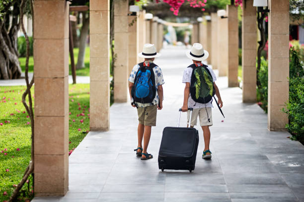 Little boy tourists walking with suitcases
