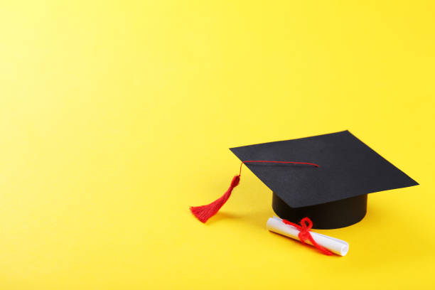 istock Graduation cap with diploma on yellow background 1140539327
