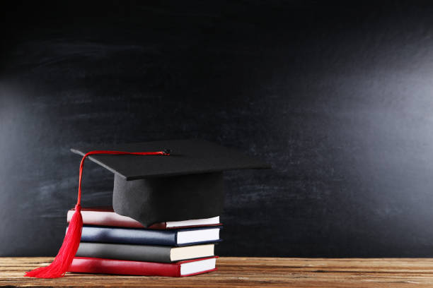 istock Graduation cap with stack of books on blackboard background 1140540130