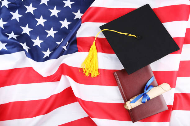 istock Graduation cap with diploma and notepad on American flag background 1140540293
