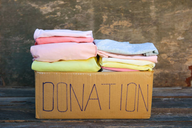 istock Donation box with clothes on the old wooden background. 1140540296