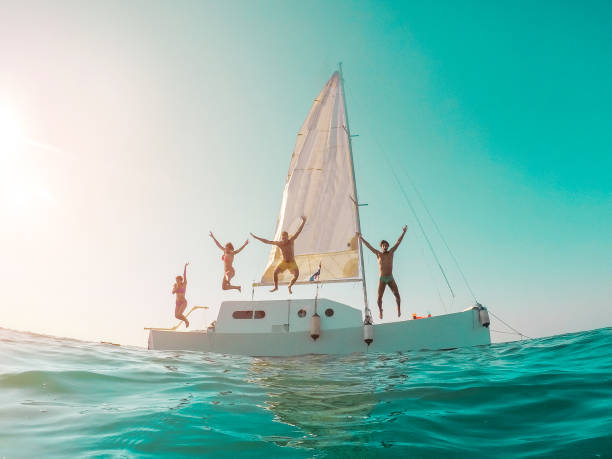 felici amici pazzi che si tuffano dalla barca a vela in mare - giovani che saltano all'interno dell'oceano durante le vacanze estive - focus principale sulle ragazze a sinistra - concetto di viaggio e divertimento - distorsione dell'obiettivo fisheye - cruise cruise ship nautical vessel florida foto e immagini stock