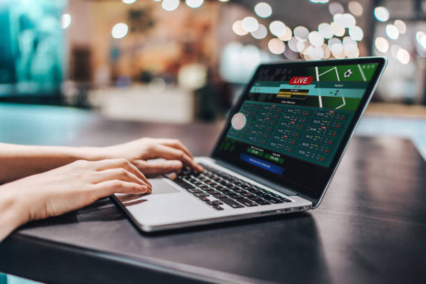 Gambling Close up crooped shot of female hands using laptop. Girl sitting in loft coffee shop and making bets online on sport bookmaker's webcite. sports betting stock pictures, royalty-free photos & images