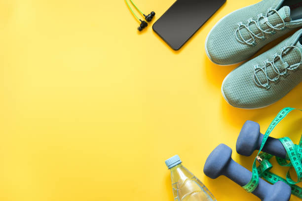 Sport and fitness equipment with sneakers and headphones on yellow. Top view. Sport and fitness equipment with sneakers and headphones on yellow. Top view, space for your text. mass unit of measurement photos stock pictures, royalty-free photos & images
