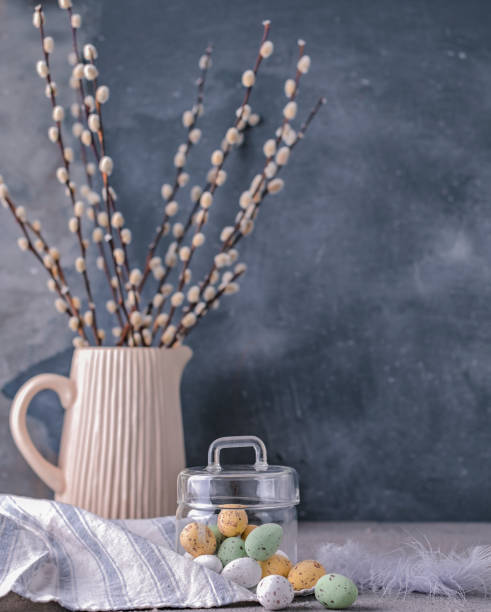 istock Willow branches in a vase on a gray background and chocolate eggs for the Easter holiday. A bunch of sprout. Card with flowers and sweets. Copy space. 1140557957