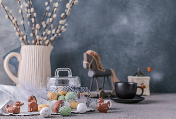 istock Willow branches in a vase on a gray background and chocolate eggs for the Easter holiday. A bunch of sprout. Card with flowers and sweets. Copy space. 1140557977