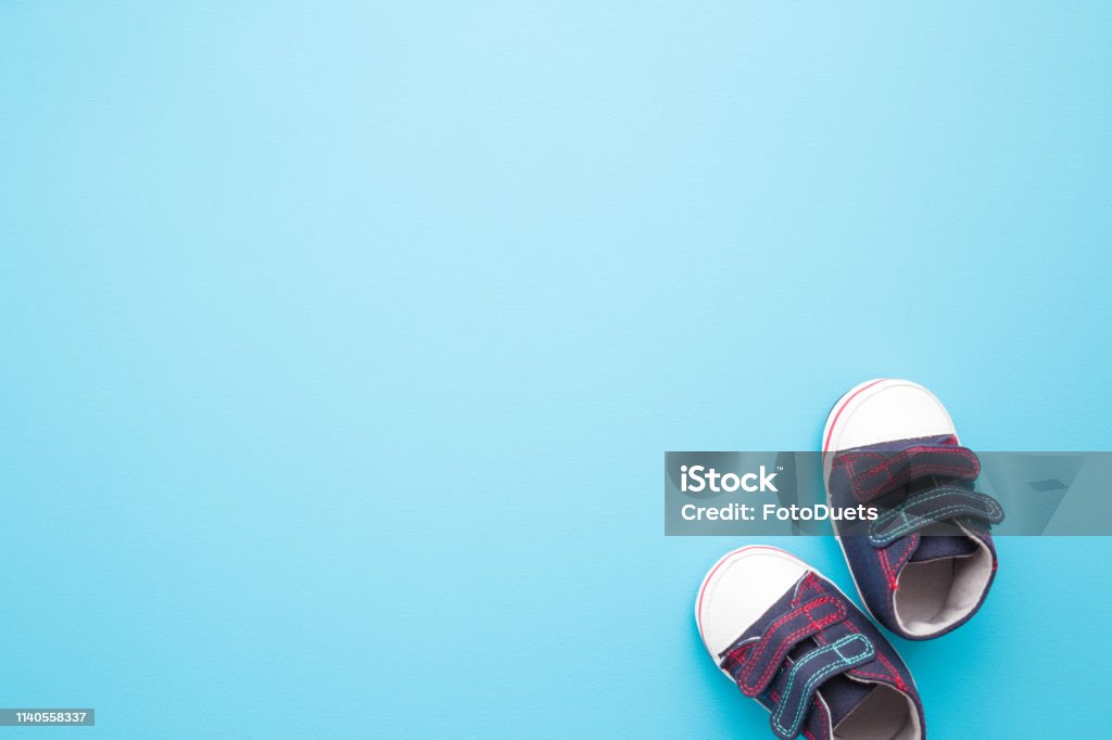 New jeans sport shoes for little kid on pastel blue background. Baby footwear. Empty place for text, quote, sayings or logo. Backgrounds Stock Photo