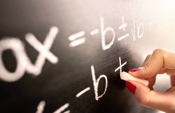 Math teacher writing function, equation or calculation on blackboard in school classroom. Student calculating on chalkboard. Substitute professor working. Tutor giving lesson. stock photo