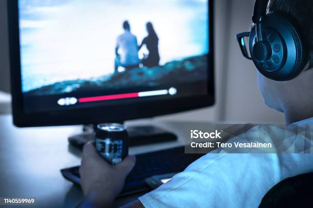 Guy Watching Movie Or Series Online From Streaming Service And Drinking Can Of Soda Internet On Demand Video Player In Computer Tv Show Episodes Marathon Late At Night Man With Headphones Stock Photo - Download Image Now
