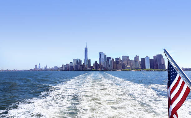ニューヨークのアメリカ合衆国の旗とクルーズ船やヨットからマンハッタンの下の眺め.ニューヨークのダウンタウンと市内中心部への眺め。スタテン島フェリー。クルージング観光客。 - lower downtown ストックフォトと画像