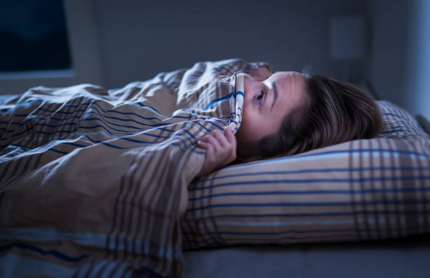 schere frau versteckt sich unter decke. angst vor der dunkelheit. nicht schlafen nach alptraum oder schlechtem traum. erwachen mitten in der nacht im schlafzimmer zu hause.  monster unter dem bett. - gruseln stock-fotos und bilder