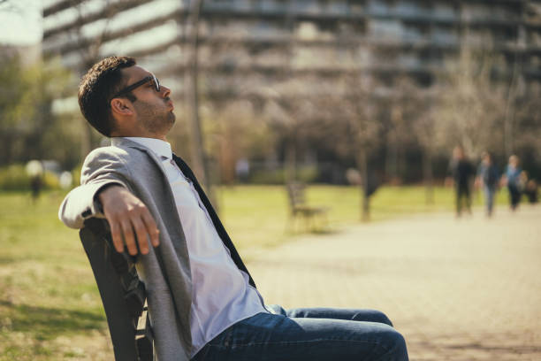 Young businessman is resting in park after work.